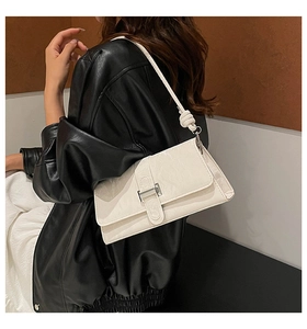 Gros plan du sac baguette en cuir blanc gaufré avec boucle argentée et bandoulière à nœuds