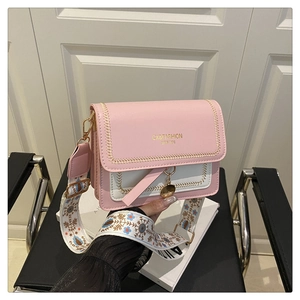 Detail of pink and white crossbody bag with embroidered wide strap and gold hardware