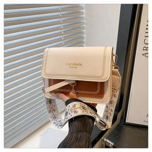 Detail of contrast flap bag featuring ethnic floral embroidery and golden metal charm