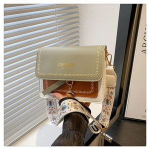 Detail of color-block crossbody bag featuring mint green flap and floral strap