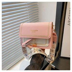 Detail of pink and beige crossbody bag featuring embroidered strap and metal pendant