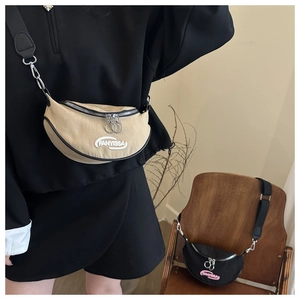 Detail of embroidered lettering and dual metal zippers on minimalist crescent crossbody bag