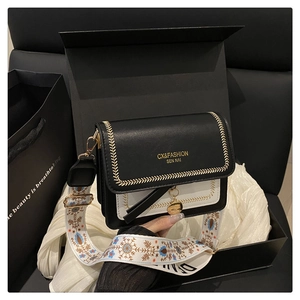 Detail of black and white crossbody bag with yellow stitching and ethnic embroidered strap