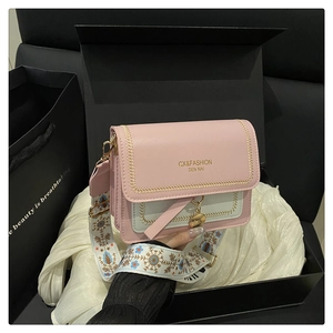 Detail of color-block crossbody bag with floral strap and gold hardware on silk