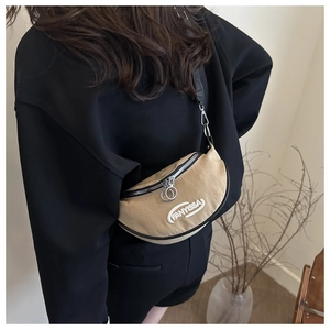 Detail of khaki crescent crossbody bag featuring FANYISSA logo and silver hardware