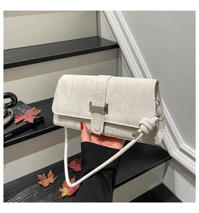 Détail du sac baguette crème marbré avec boucle métallique carrée et nœud sur la bandoulière