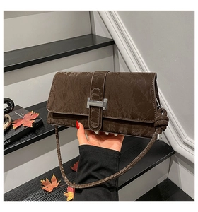 Détail d'un sac à bandoulière en cuir plissé marron foncé avec fermoir argenté rétro