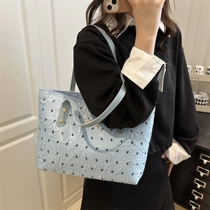 Light blue pleated tote bag with black bow patterns shown in a mirror selfie perspective
