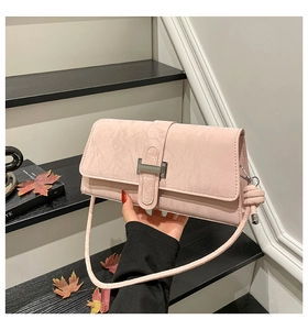 Détail d'un sac bandoulière rose clair avec texture marbrée et boucle métallique argentée