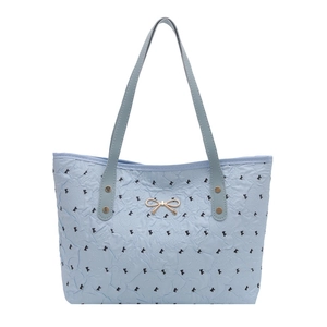 Sac fourre-tout matelassé bleu clair avec motifs noirs et nœud doré sur le devant