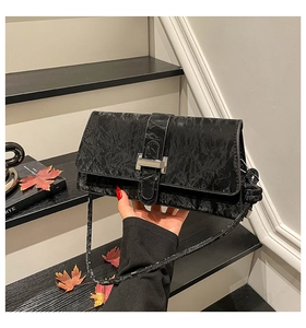 Détail du sac à main en cuir froissé noir avec boucle argentée et bandoulière fine