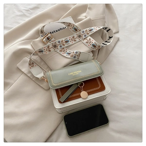 Detail of color-block crossbody bag with bohemian embroidered wide strap and metal charm