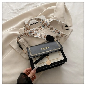 Detail of crossbody bag with floral embroidered strap and gold metallic hardware