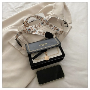 Detail of a retro contrast color crossbody bag with floral embroidered wide shoulder strap