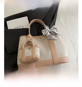 Detail of beige canvas tote with leather trim, mini pouch, and silk scarf decoration