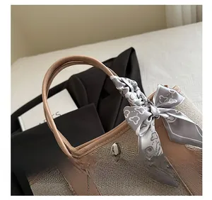 Detail of canvas tote bag showing the leather handle, silver studs, and stylish silk scarf