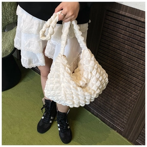 Close-up of creamy white hobo bag with bubbly pleat texture and soft elastic fabric