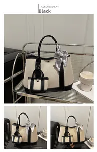Detail of beige canvas tote with black leather trim, printed scarf, and mini charm bag