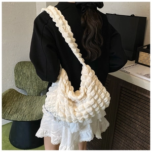 Detailed view of a white pleated cloud hobo bag with wide shoulder strap on a model