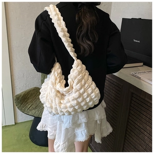 Back view of a model wearing a white puffy bubble shoulder bag with ruched texture