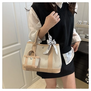 Detail of canvas tote bag with leather trim and decorative silk ribbon handle