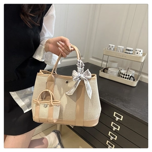 Detail of beige canvas tote bag with brown leather trim and patterned silk scarf accent