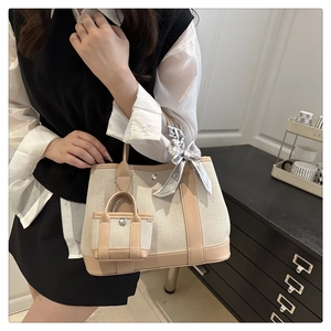 Detailed shot of canvas tote bag with brown leather trim and decorative silk scarf accessory