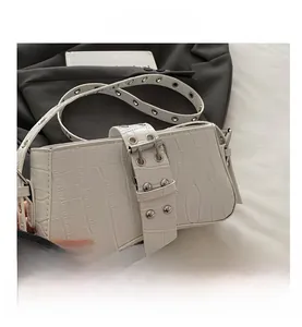 Detail of white crocodile texture bag featuring silver rivets and eyelet strap