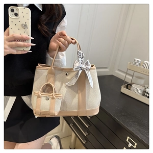 Detail of beige canvas tote bag with brown leather trim, mini pouch, and floral silk scarf