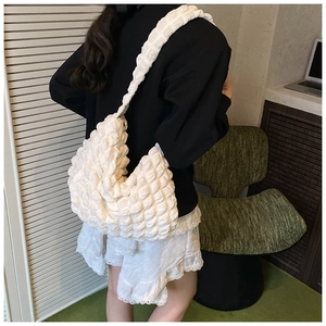 Close-up of white bubble textured tote bag with pleated fabric and wide shoulder strap