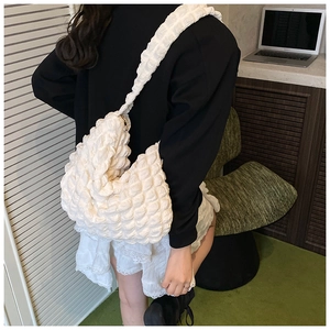 Detailed side view of a white popcorn texture shoulder bag with wide strap on a model