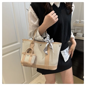 Close-up of canvas tote bag with leather trim, featuring a mini pouch and printed silk scarf