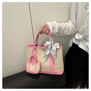 Detail of canvas tote bag with pink leather trim and decorative silk scarf accessory