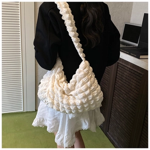 Detail of white popcorn textured shoulder bag showing pleated fabric and strap