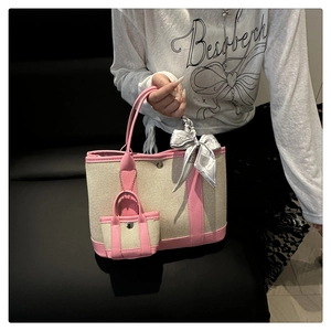 Detail of canvas tote bag with pink leather trim, decorative scarf and mini bag charm