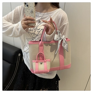 Detail of canvas tote bag with pink leather trim, silk scarf handle, and mini bag charm