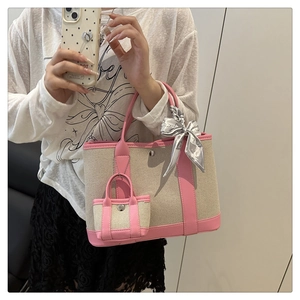 Detail of canvas tote bag with pink trim, silk scarf decor and mini charm accessory