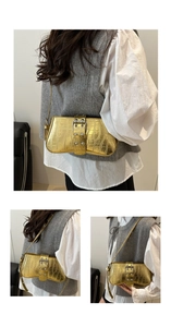 Detail of golden crocodile pattern shoulder bag with metallic buckle and glossy texture