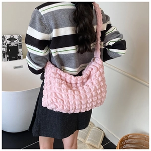 Close-up of pink puffy cloud shoulder bag featuring textured bubble fabric on a model