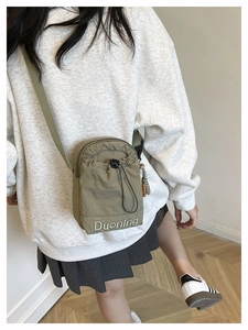 Sac bandoulière en nylon vert olive avec cordon de serrage porté par un mannequin