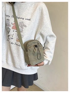 Vue détaillée du petit sac bandoulière en nylon vert olive avec logo brodé et cordon de serrage