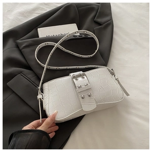 Detail of white crocodile pattern bag with silver studs and metal buckle on grey blazer