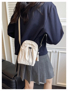 Detail of beige nylon crossbody bag featuring drawstring closure and side fashion label