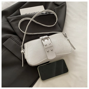 Detail of white crocodile pattern shoulder bag with wide metal buckle and adjustable strap
