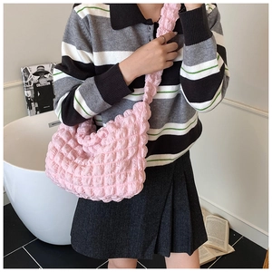 Detail of soft pink puff pleated shoulder bag shown in a cozy indoor lifestyle setting