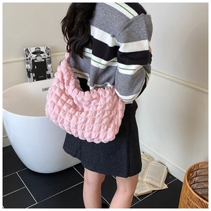 Pink pleated bubble shoulder bag styled with a striped sweater in a lifestyle setting