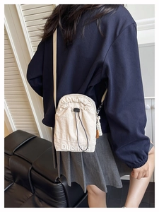 Détail du sac à bandoulière en nylon crème avec cordon de serrage et broderie de lettres
