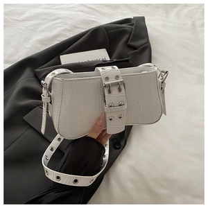 Detail of white crocodile pattern shoulder bag with silver eyelets and buckle accents