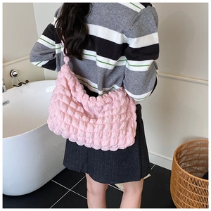 Detailed view of pink bubble pleated hobo bag worn on shoulder in a bright setting