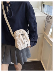 Détail du sac seau beige à cordon avec broderie blanche et fine bandoulière noire